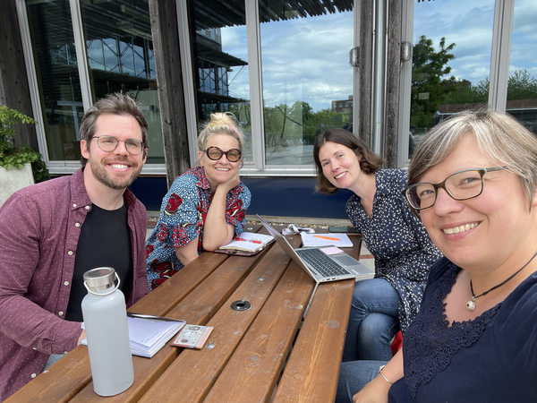 Current working group sitting around a picnic table outdoors. Image.