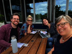 Current working group sitting around a picnic table outdoors. Image.