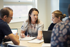 Studenter kring ett bord, försjunkna i diskussion.